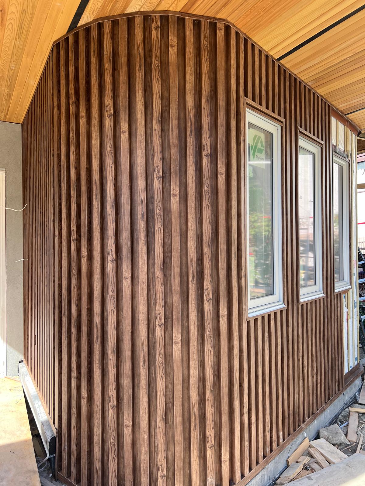 Curved exterior wall finished in dark vertical wood-look siding